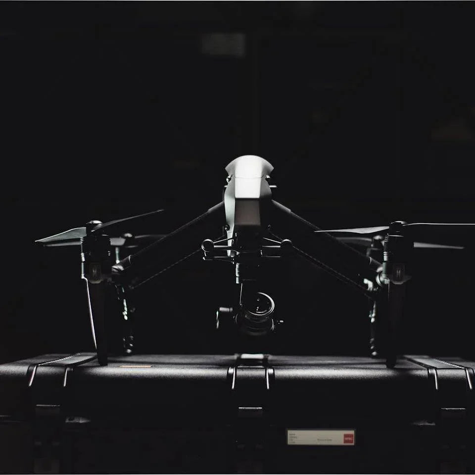 Black professional drone with camera mounted on top of a hard carrying case in dark background