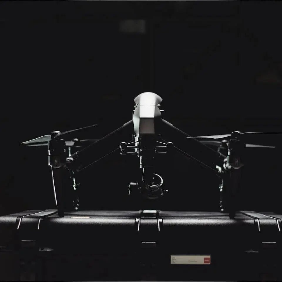 Black professional drone with camera mounted on top of a hard carrying case in dark background