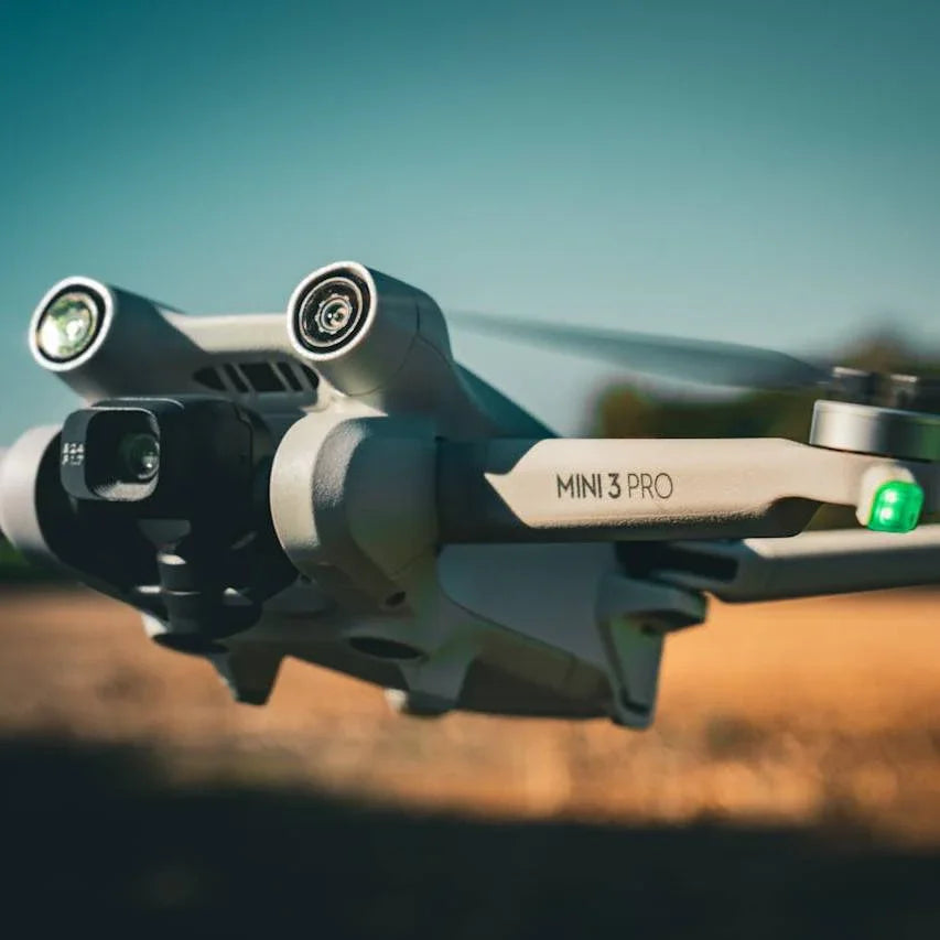 Close-up of Mini 3 Pro drone in flight with dual cameras and green indicator light, clear sky background