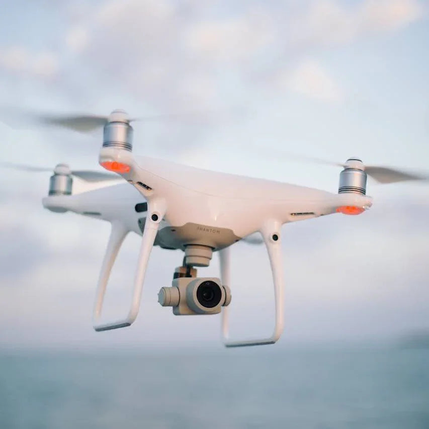 white DJI Phantom drone flying over water with camera, blue sky background