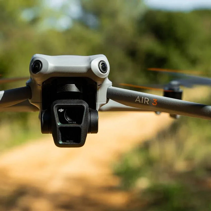 Close-up of DJI Air 3 drone flying outdoors with dual camera system and blurred natural background